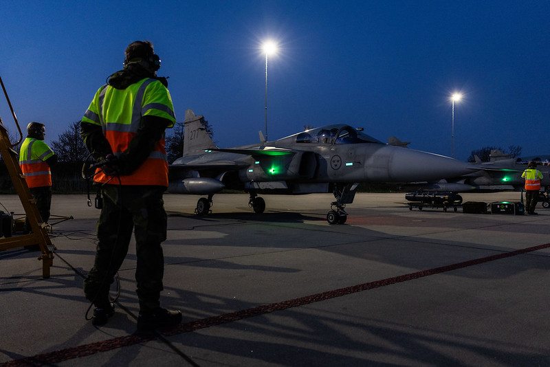 A equipe de solo da Força Aérea Sueca aguarda enquanto os caças JAS 39 Gripen se preparam para taxiar para decolar na Base Aérea de Leeuwarden, na Holanda, durante o exercício Ramstein Flag 25.