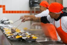 Cozinheiros servindo comida nas marmitas, alimentação