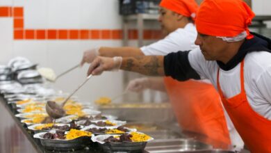 Cozinheiros servindo comida nas marmitas, alimentação